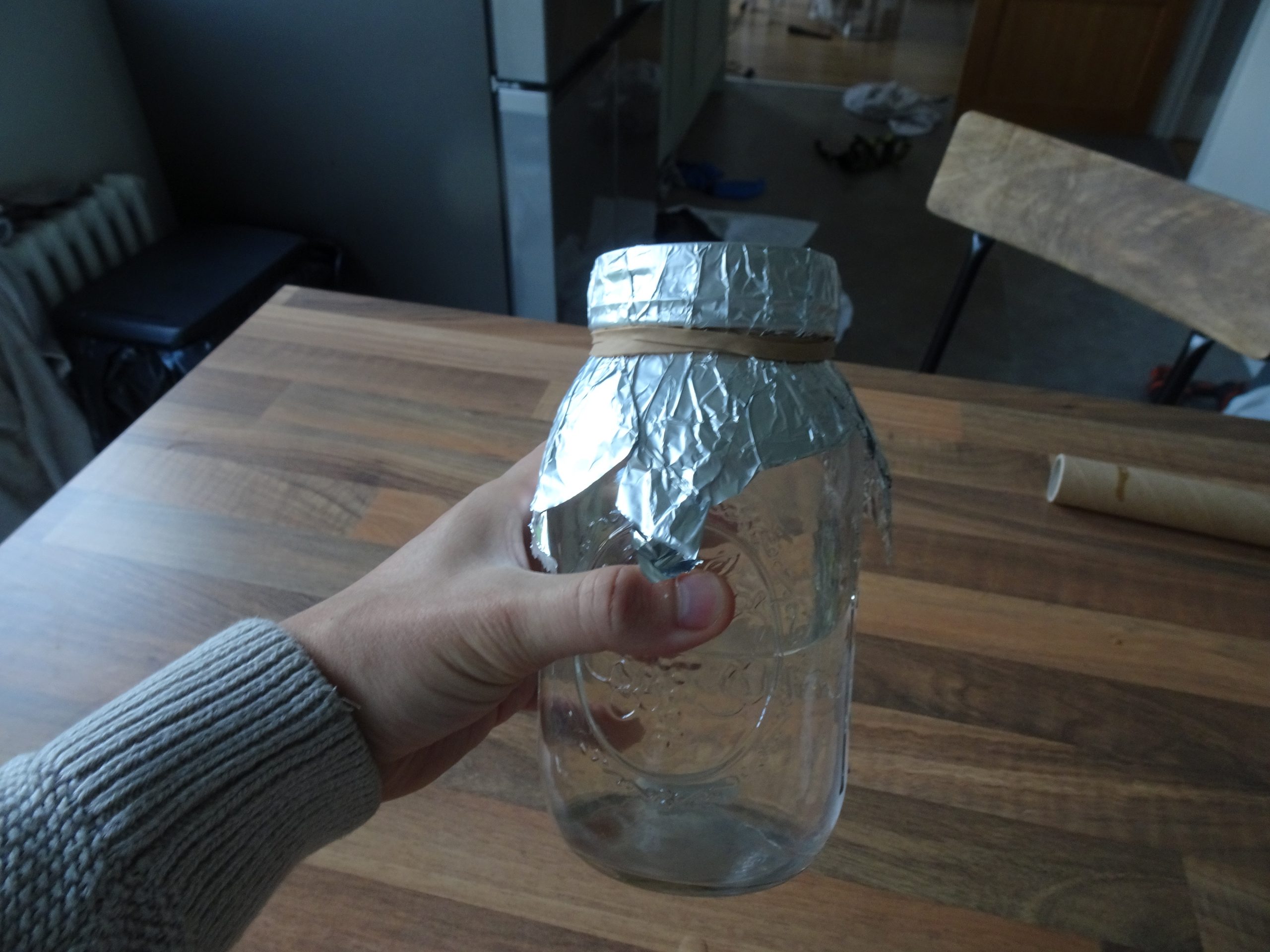 Jar held in hand with foil over top